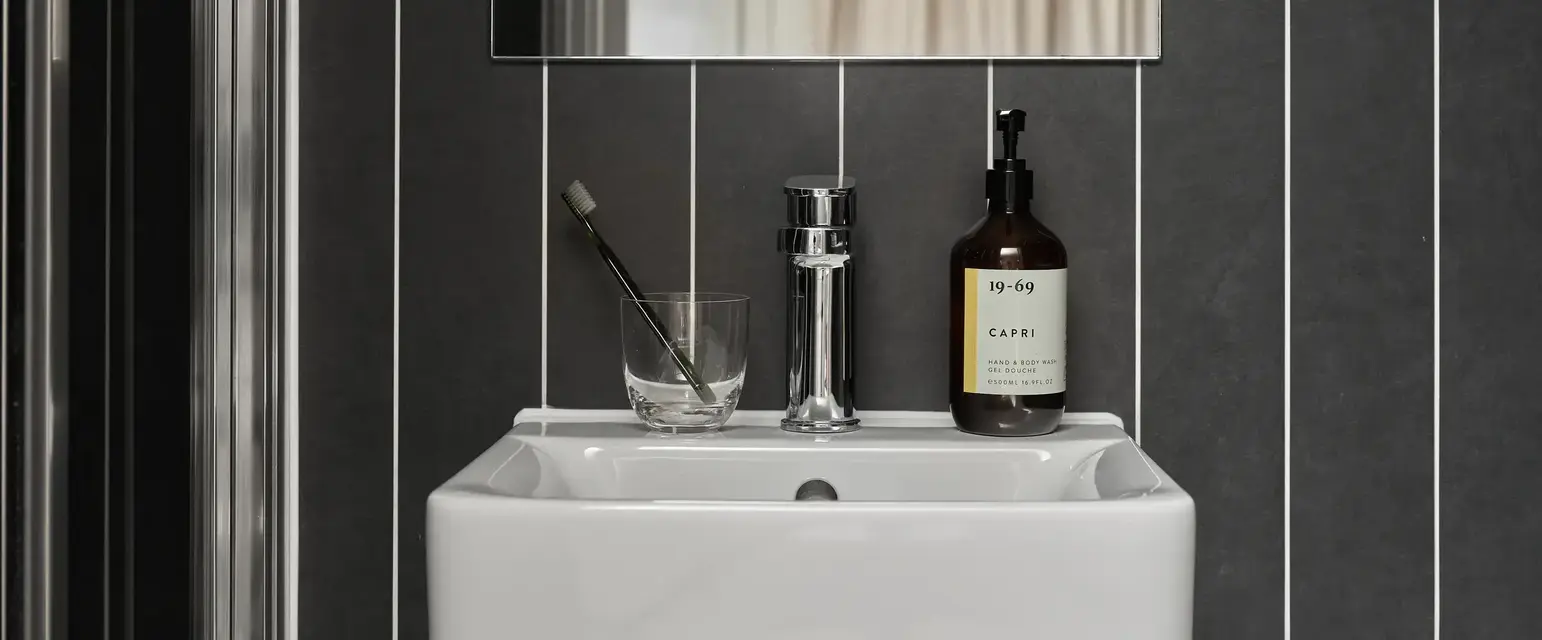 a sink with a mirror and a bottle of liquid on it