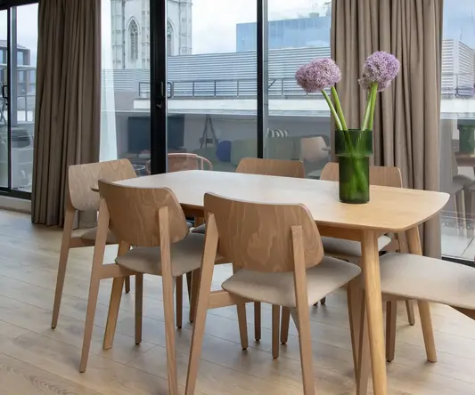 a table with chairs and flowers in a room with windows