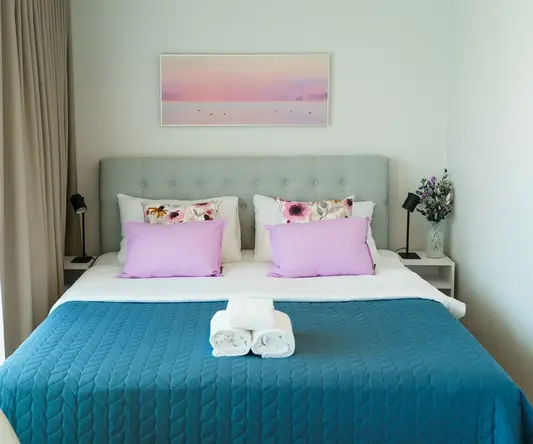 a bed with a blue blanket and towels on it