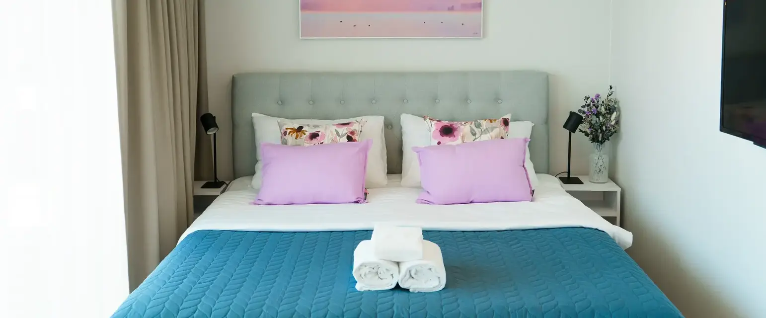 a bed with a blue blanket and towels on it