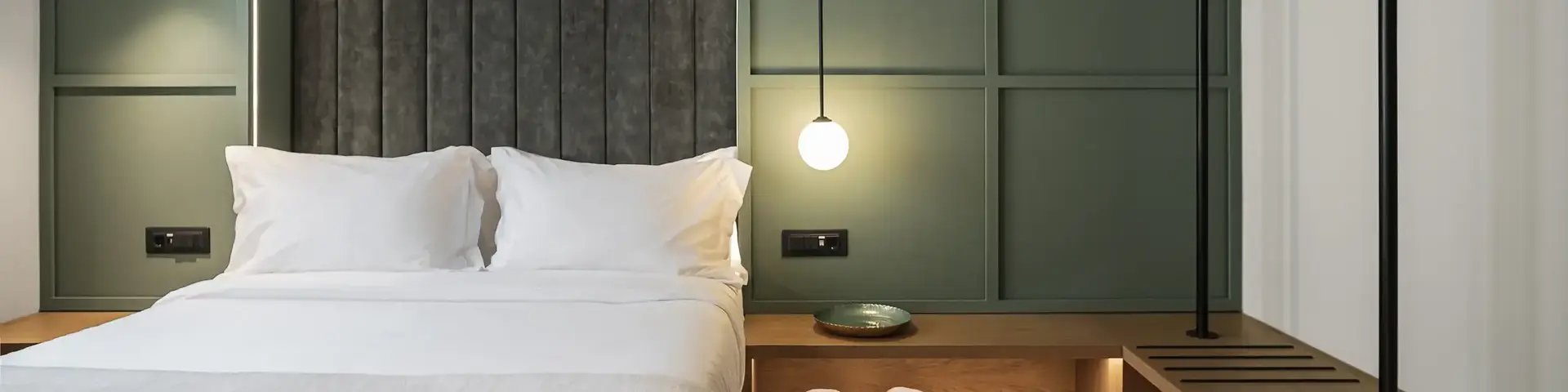 a bed with white sheets and a shelf with towels