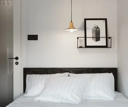 a bed with pillows and a light from the ceiling