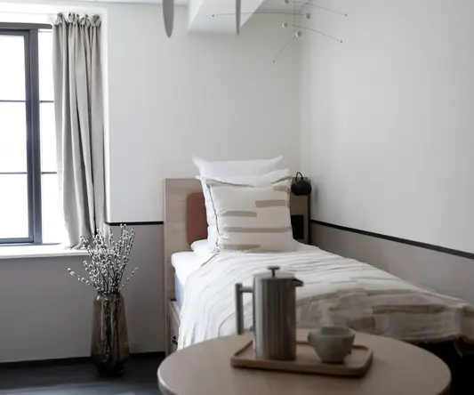 a small bed with a coffee pot and a vase of flowers