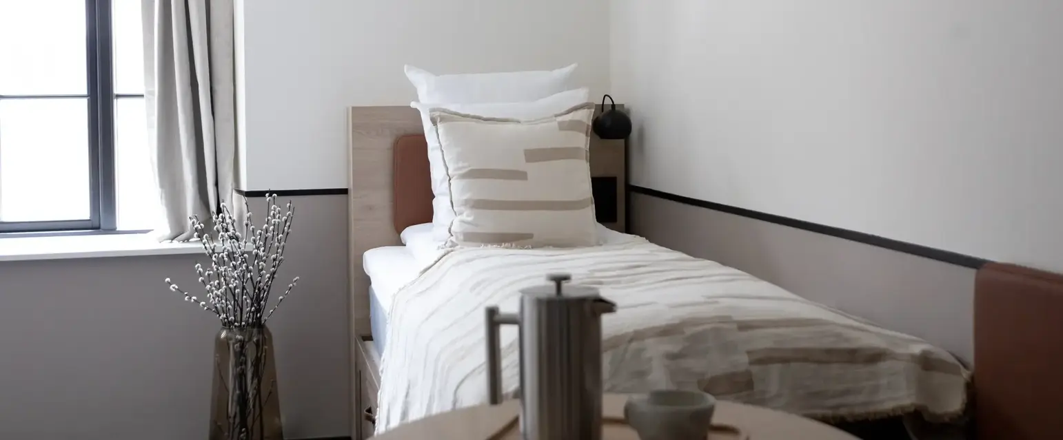 a small bed with a coffee pot and a vase of flowers