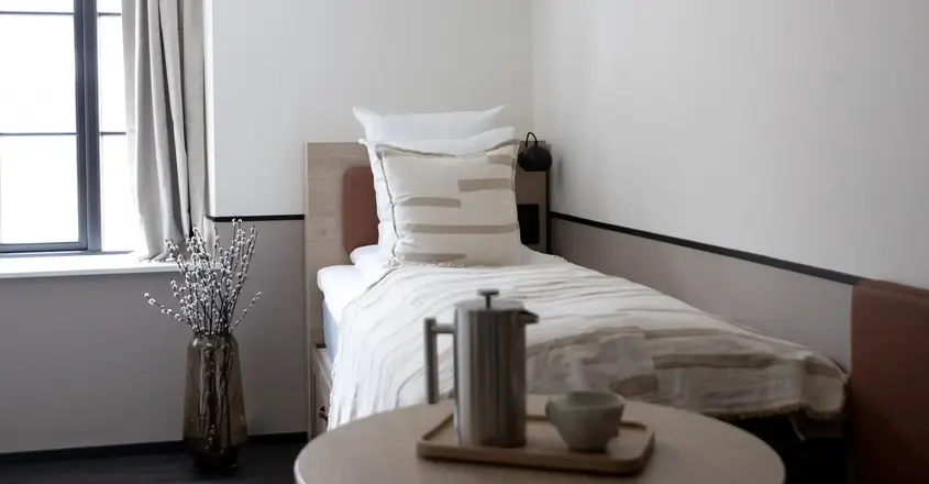 a small bed with a coffee pot and a vase of flowers