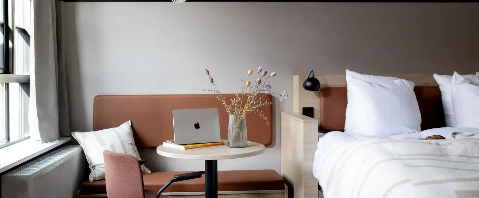 a room with a bed and a laptop on a table