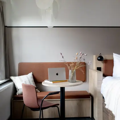 a room with a bed and a laptop on a table