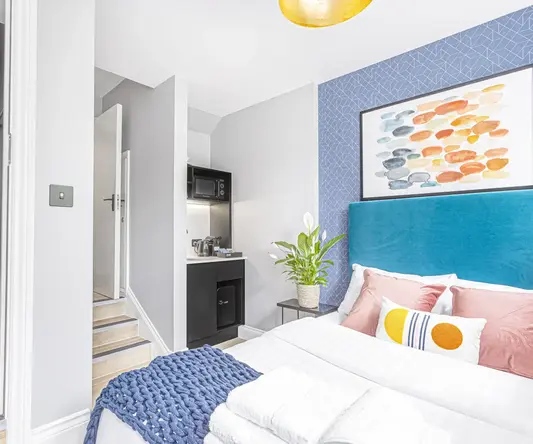 a bed with a blue headboard and a painting on the wall