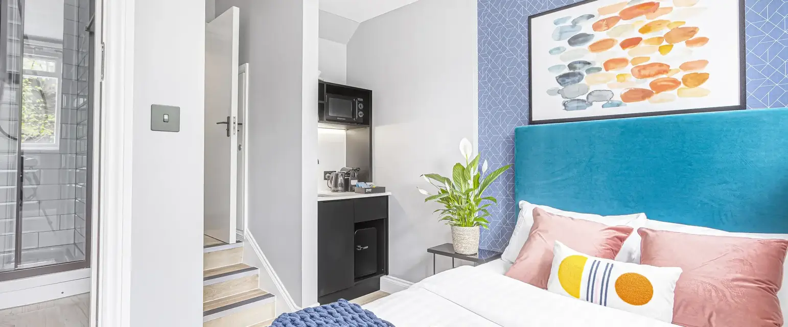 a bed with a blue headboard and a painting on the wall