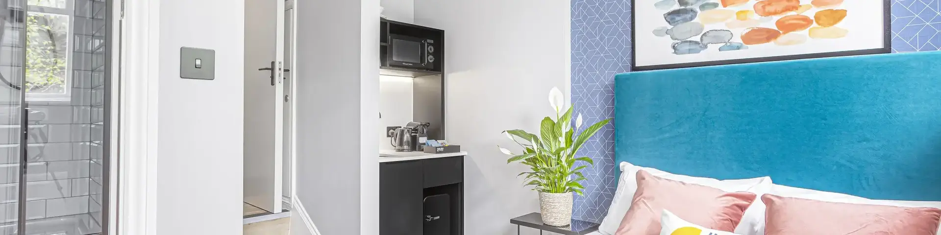 a bed with a blue headboard and a painting on the wall