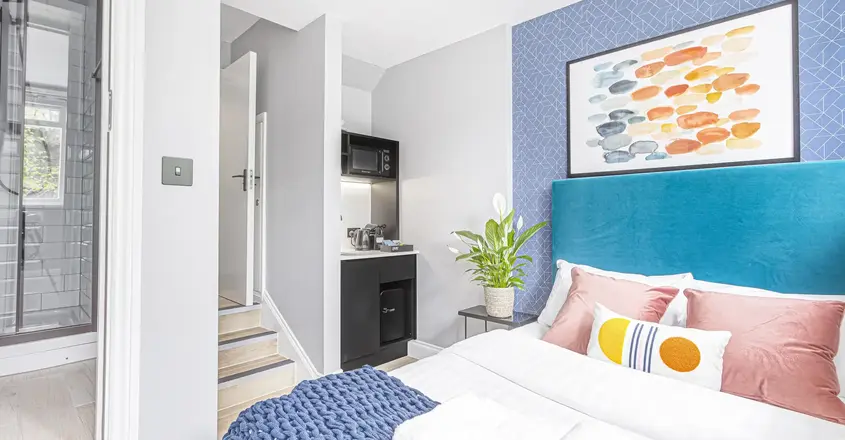 a bed with a blue headboard and a painting on the wall