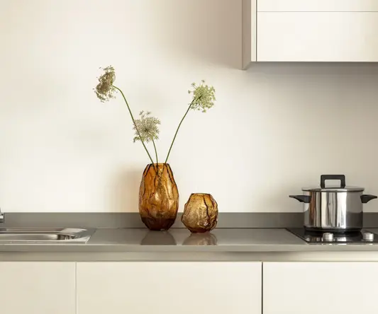 two vases with flowers on a counter