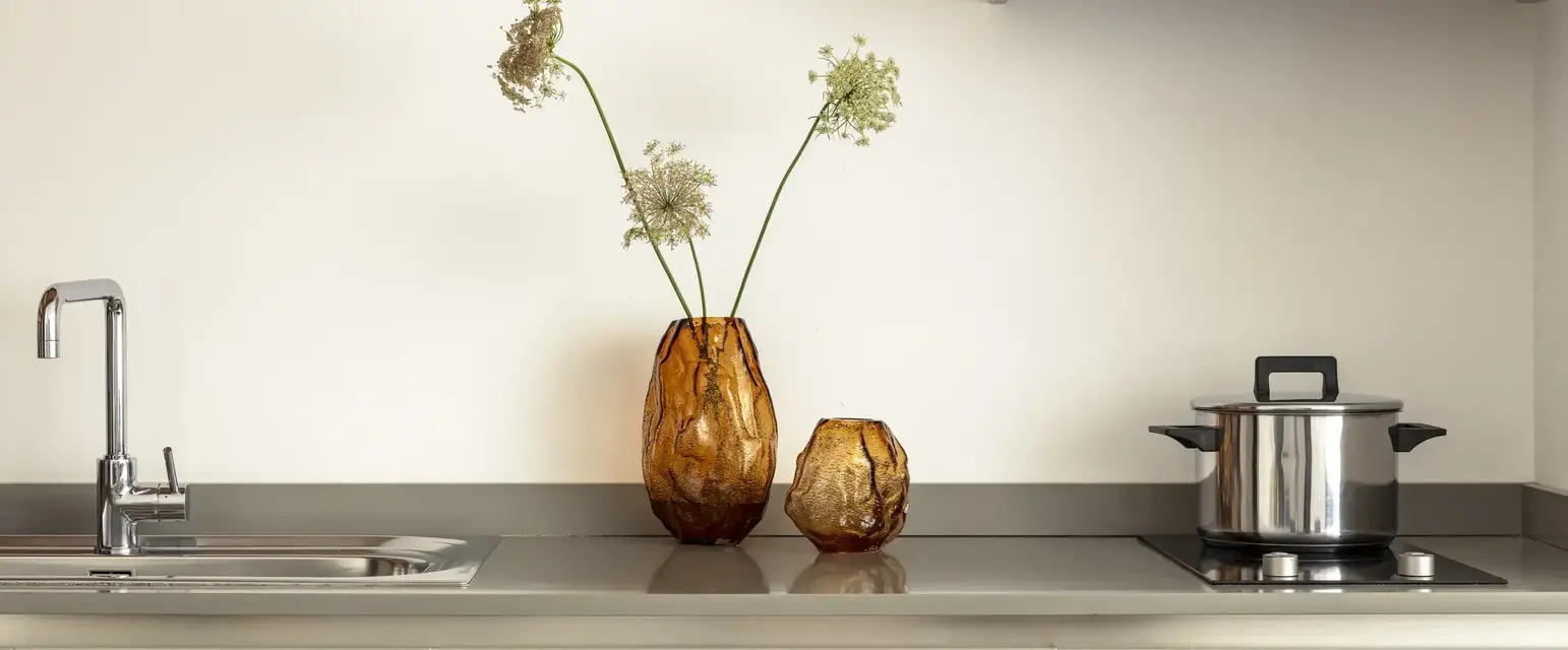 two vases with flowers on a counter