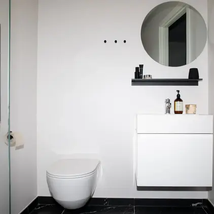 a bathroom with a round mirror and a toilet