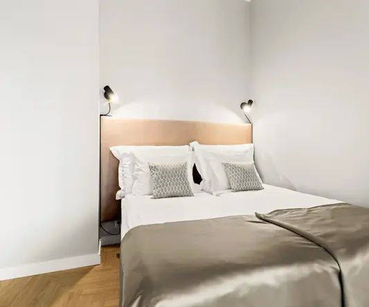 a bed with pillows and a light on the wall