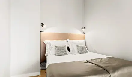 a bed with pillows and a light on the wall