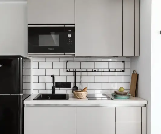 a kitchen with white cabinets and black appliances