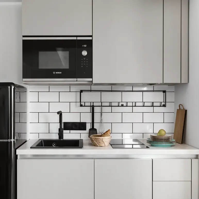 a kitchen with white cabinets and black appliances