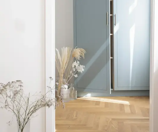 a closet door with a shelf and dried flowers in a room