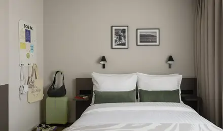 a bed with pillows and a suitcase on the side