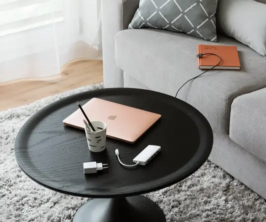 a coffee table with a laptop and a charger on it