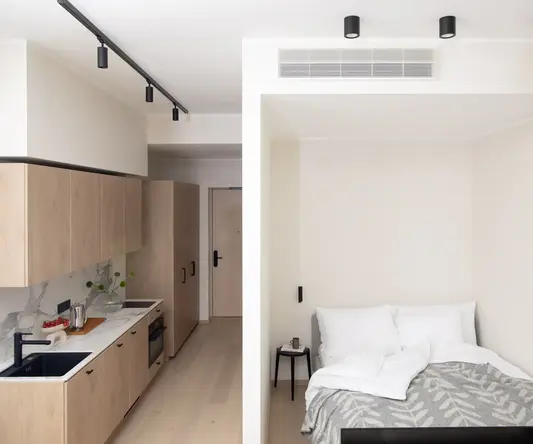 a small room with a bed and kitchen