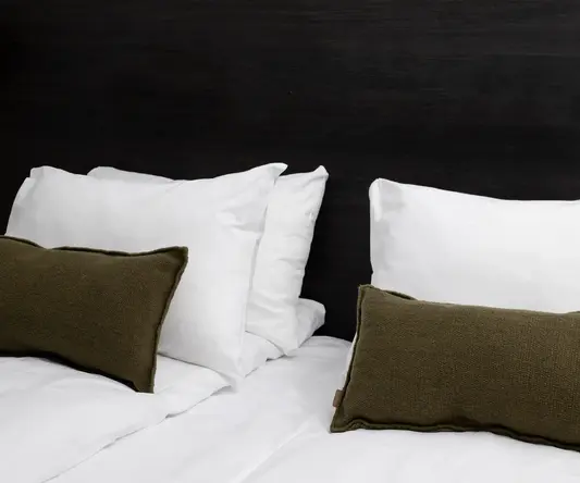 a bed with white sheets and pillows