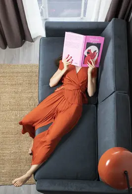 Lady lying on a sofa reading a book