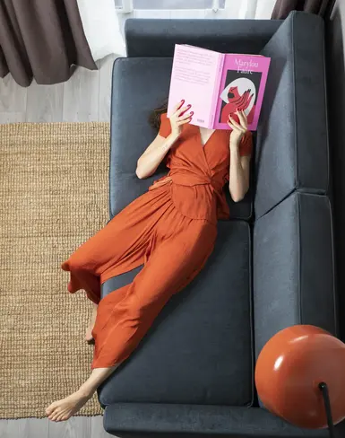 Lady lying on a sofa reading a book