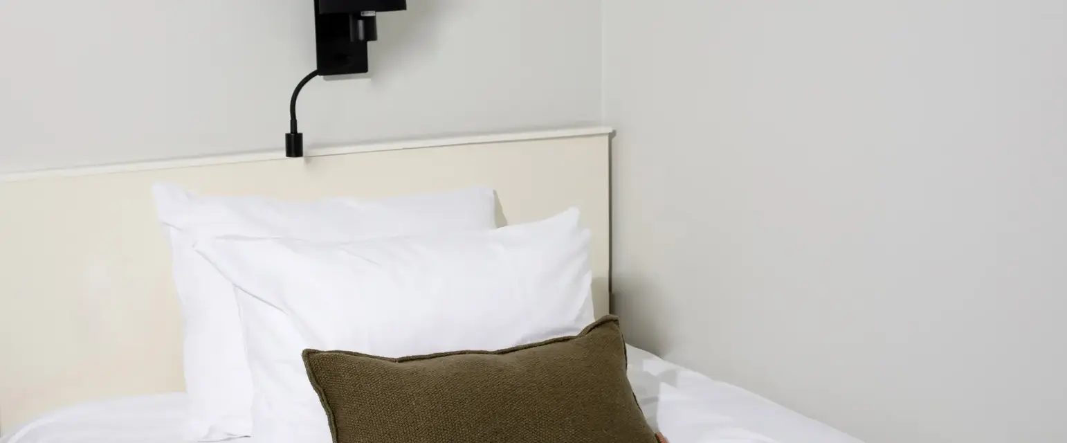 a bed with pillows and a lamp