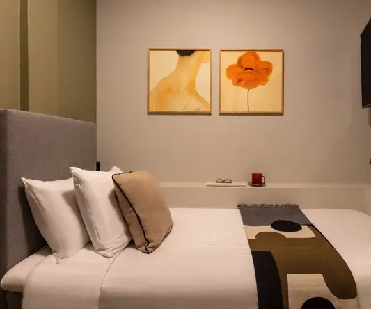 a bed with pillows and a blanket in a room with art on the wall