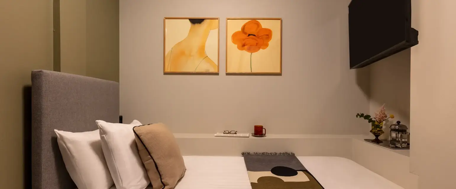 a bed with pillows and a blanket in a room with art on the wall
