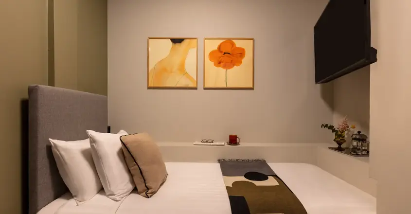 a bed with pillows and a blanket in a room with art on the wall