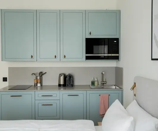 a kitchen with blue cabinets and a bed