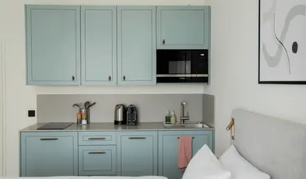 a kitchen with blue cabinets and a bed