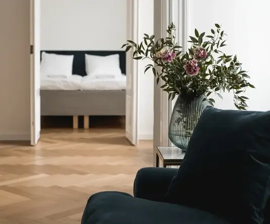 a vase of flowers in front of a bed