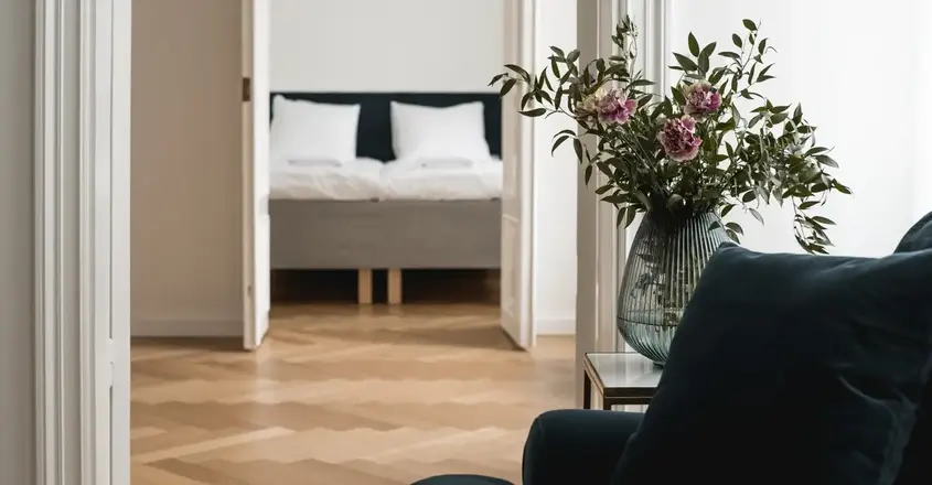 a vase of flowers in front of a bed