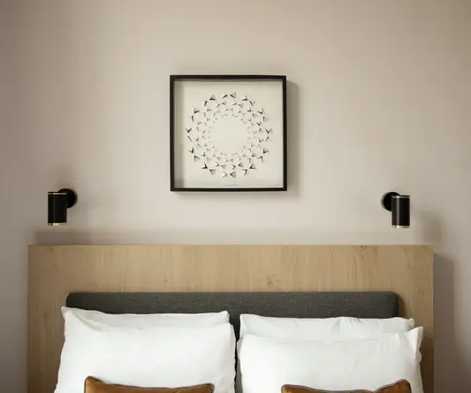 a bed with pillows and a picture on the wall