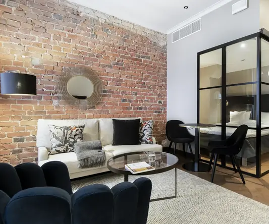 a room with a brick wall and a couch and a glass cabinet