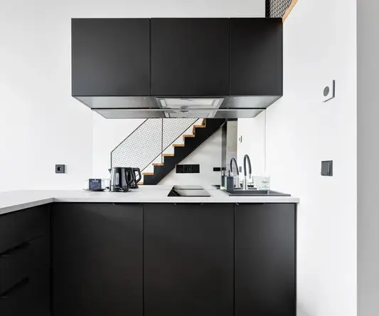 a kitchen with black cabinets and a staircase