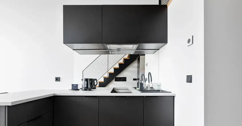 a kitchen with black cabinets and a staircase