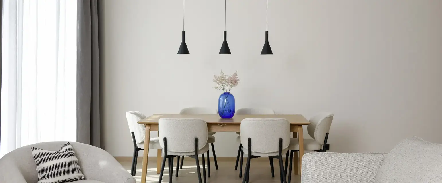 a dining table with chairs and a blue vase