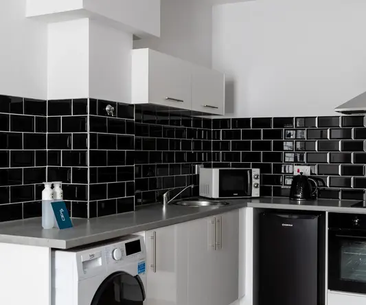a kitchen with black tile walls and white cabinets