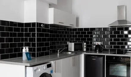 a kitchen with black tile walls and white cabinets