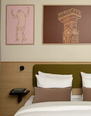 a bed with pillows and a table with artwork on the wall