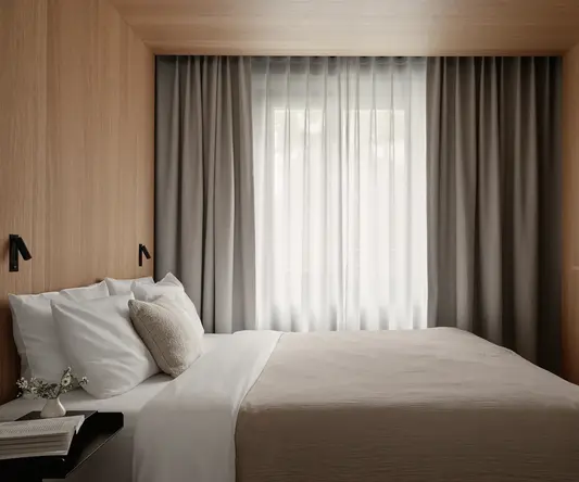 a bed with a pillow and a table in a room with curtains