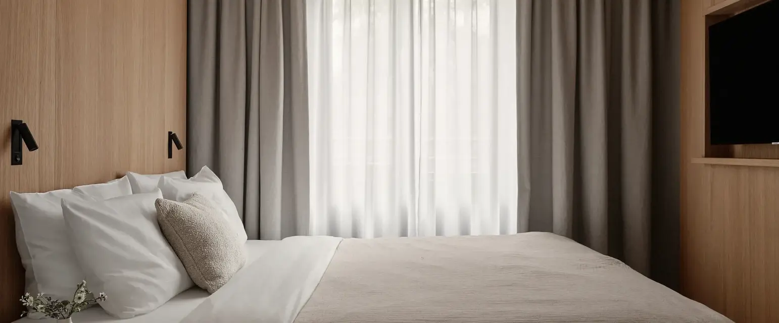 a bed with a pillow and a table in a room with curtains