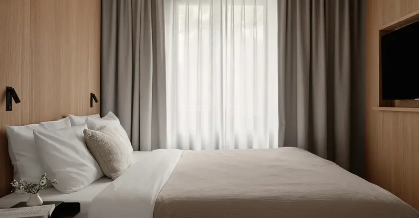 a bed with a pillow and a table in a room with curtains