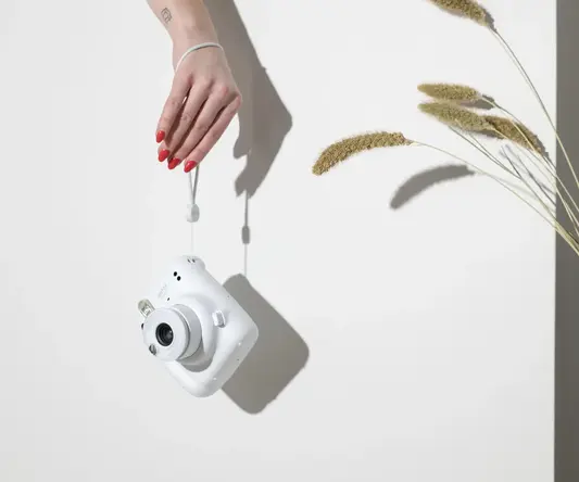 a hand holding a white camera