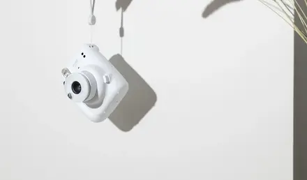 a hand holding a white camera